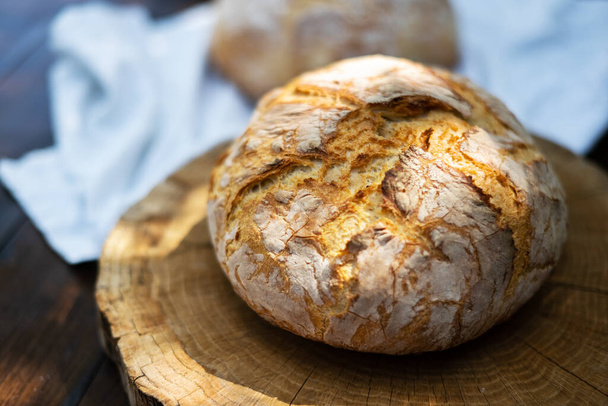 Geleneksel mayalanmış mayalı ekmek. Köy ahşap bir masada derisi pişmiş. Sağlıklı yemek fotoğrafçılığı - Fotoğraf, Görsel
