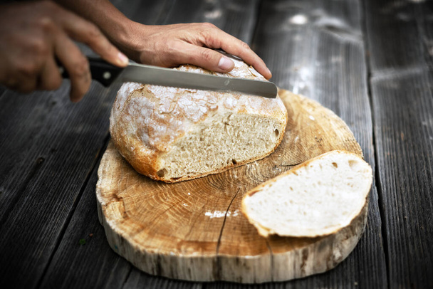 Traditional leavened sourdough bread cut into slice on a rustic wooden table. Healthy food photography - Fotoğraf, Görsel