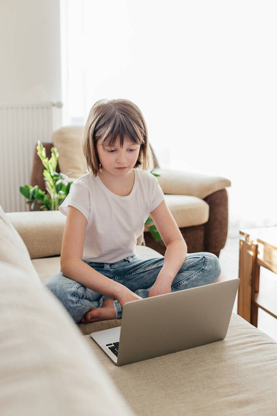 Mesafe öğrenme. İnternette okuyan kız öğrenci ya da internetten bilgisayar kullanarak iletişim kuran. Çevrimiçi evde eğitim gören çocuklar kavramı - Fotoğraf, Görsel