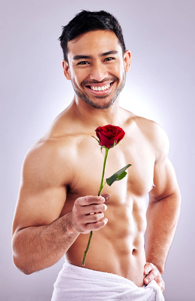 I hope youll accept this rose. Studio shot of a handsome young man posing with a red rose - Fotoğraf, Görsel