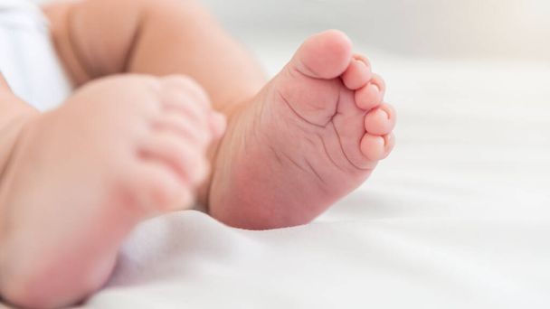 Close up little tiny baby with chubby foots over a sheets bed. Peace calm infant toddler newborn boy sleep resting take deep nap laying on soft white blanket. Family maternity concept - Φωτογραφία, εικόνα