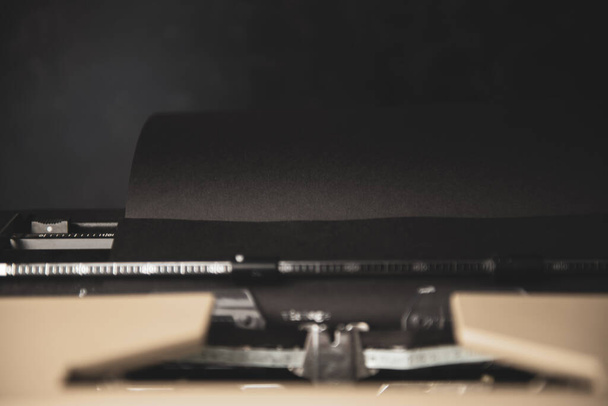 Vintage typewriter with black paper and white ink showing the word vintage. Dark background. High quality photo - Φωτογραφία, εικόνα