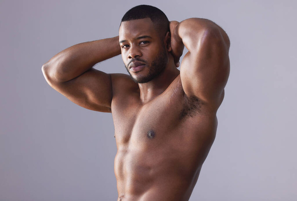 I couldnt hear you over the volume of my muscles. Studio shot of a handsome and muscular young man posing against a grey background - Foto, immagini