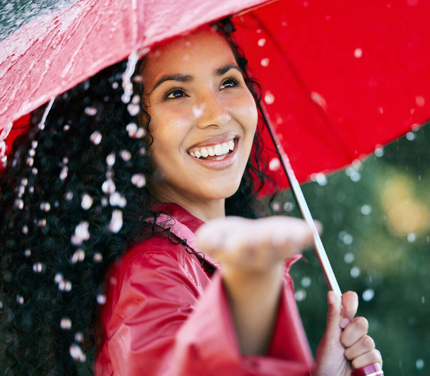 Surrounded by showers of blessings. a beautiful young woman standing in the rain with an umbrella - Foto, imagen