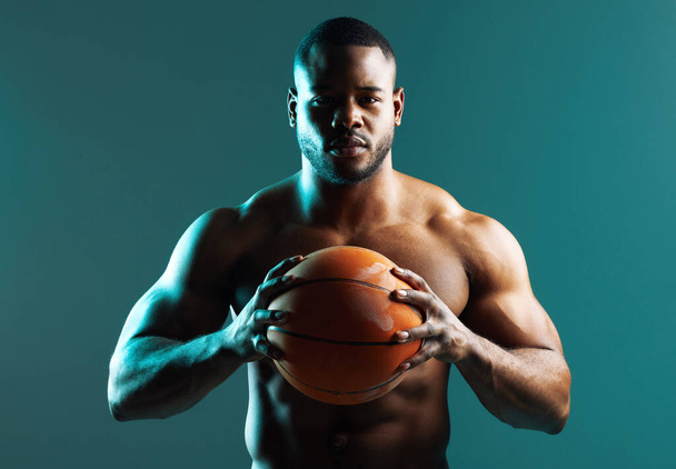 Lets see what you can do with this ball. Studio shot of a.muscular young man playing basketball against a green background - Photo, image