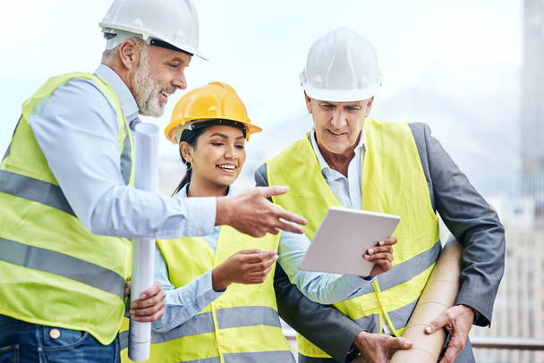 Monitoring workflow directly from their tablet. a group of businesspeople using a digital tablet while working at a construction site - Photo, Image