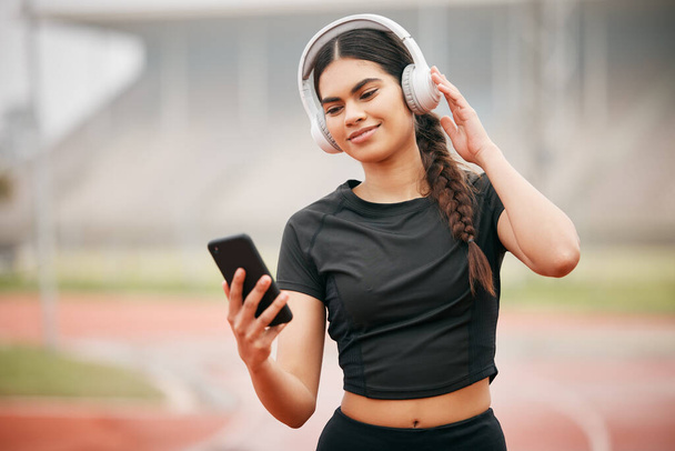How do I do it With the right playlist. an athletic young woman holding her cellphone while listening to music through her headphones - Photo, Image