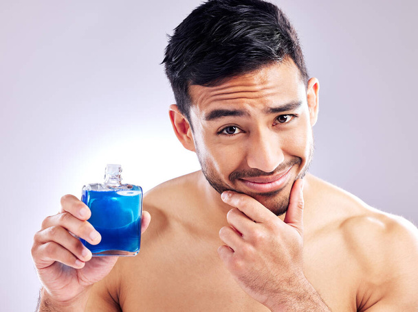 I suggest you try it out. Studio shot of a handsome young man applying aftershave - 写真・画像