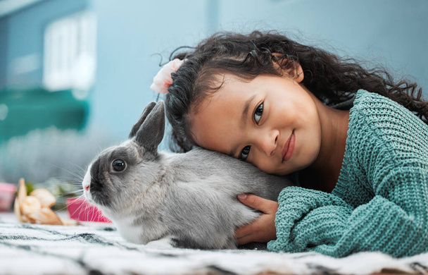 My pet rabbit loves hugs. an adorable little girl bonding with her pet rabbit at home - Фото, изображение