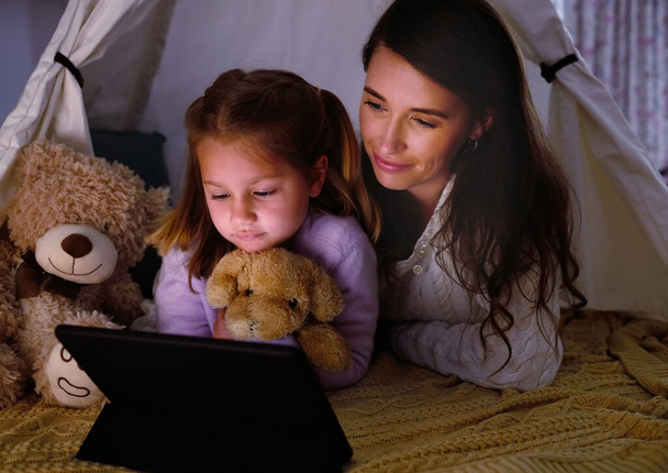 Just one more episode before bedtime. a little girl and her mother watching something on a digital tablet at night - Foto, imagen