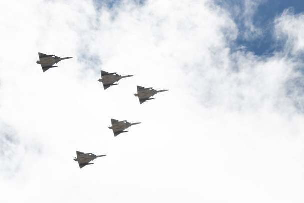 Close up to a five Kfir jet combat planes flight in "V" formation with cloudy and blue sky at background - Fotó, kép