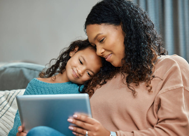 What do you feel like watching today. an attractive young woman sitting and bonding with her daughter while using a digital tablet - Foto, imagen