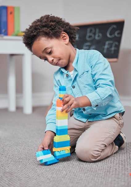 I want to have the tallest building in the city. a young boy playing with building blocks in a room - Photo, image