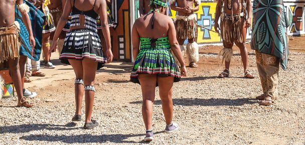 Performers from waist down in on street in colorful costume in South African cultural tourist attraction - 写真・画像