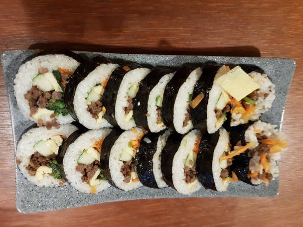 Gimbap is a Korean food made from steamed white rice and various other ingredients, rolled in gim. On the plate. - Photo, Image