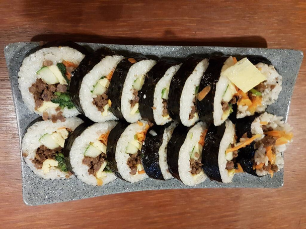 Gimbap is a Korean food made from steamed white rice and various other ingredients, rolled in gim. On the plate. - Foto, Imagen