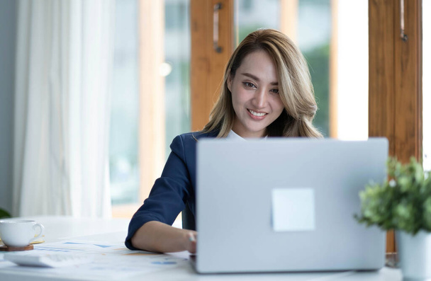 Charming asian businesswoman sitting working on laptop in office - Foto, Imagen