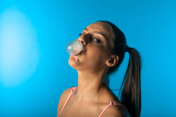 Detailní záběr krásné dívky tvorby žvýkačky balón ve studiu - Fotografie, Obrázek