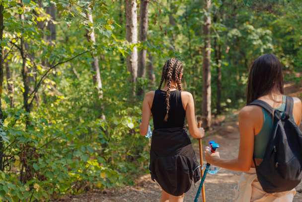 Hermanas caminando por hermosos bosques mientras usan una mochila y disfrutan de la naturaleza. Vinculación femenina. - Foto, Imagen