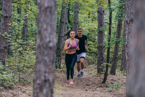 Apto atletas masculinos e femininos correndo na natureza. Natureza e conceito desportivo. - Foto, Imagem