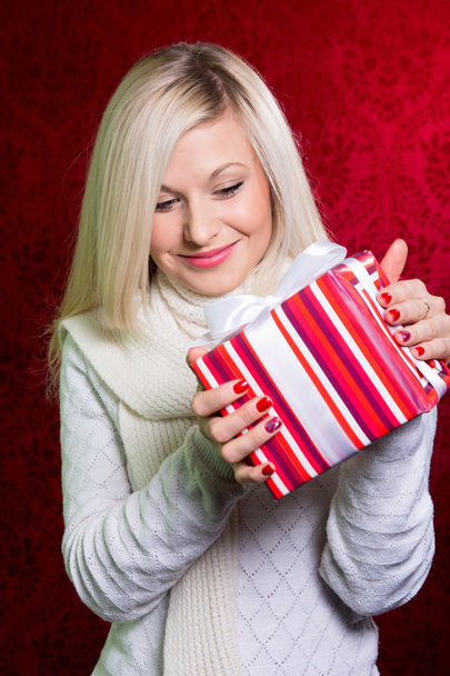 A girl in a white sweater and striped gift with white bow  - Φωτογραφία, εικόνα