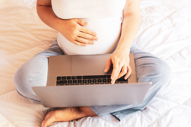 App per computer in gravidanza. Donna incinta con un portatile digitale in mano. Mobile gravidanza applicazione notebook maternità online. Concetto maternità, gravidanza, parto - Foto, immagini
