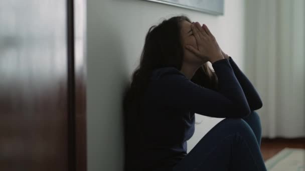 Kadın duygusal bir acı hissediyor evde oturmuş çaresiz bir şekilde utançla yüzünü kapatıyor. - Video, Çekim