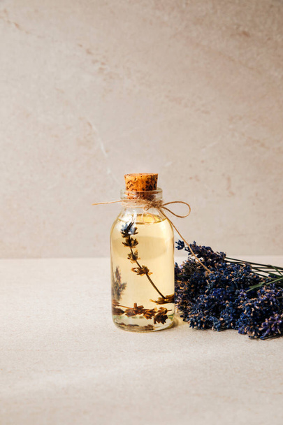 Lavender oil on light stone background with lavender flowers. Front view - Valokuva, kuva