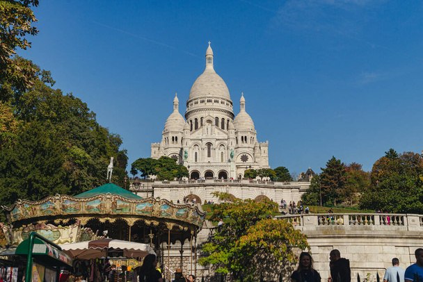 An exterior shot of the white Sacred Heart of Paris, Sacre-Coeur with trees and a blue sunny sky, Paris, France - Valokuva, kuva