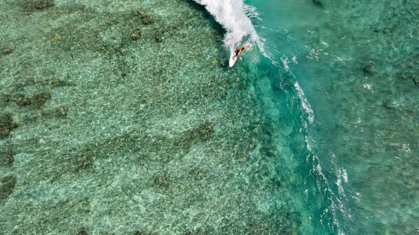 An aerial view of a male surfer riding the huge waves - 写真・画像