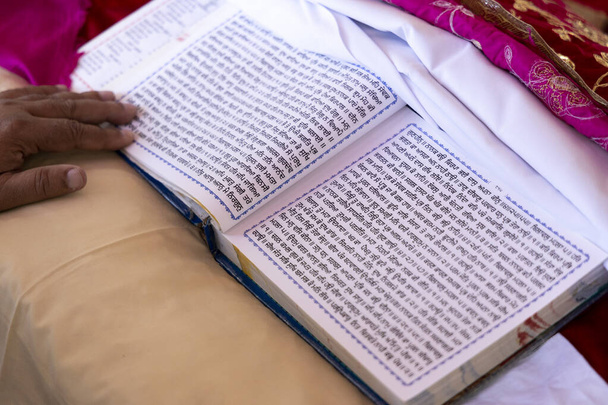 Гуру Грант Сахіб Святе релігійне Писання сикхізму. Мова пенджабі, написана на релігійних білих сторінках під час весільної церемонії.. - Фото, зображення
