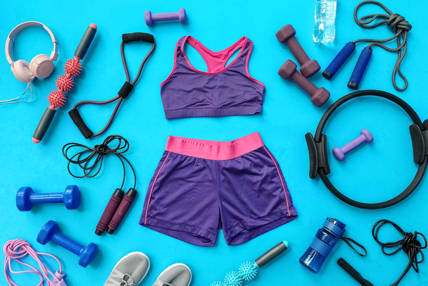 Kadın spor kıyafetleri ve mavi arka planda pilates için farklı ekipmanlar. - Fotoğraf, Görsel