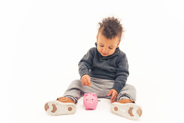 Beautiful afro american child putting a coin into a piggy bank - isolated. High quality photo - Fotó, kép