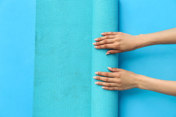 Female hands with yoga mat on color background - Photo, Image