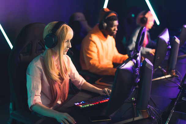Three teenagers wearing colorful clothes playing online game together wearing headsets using professional gaming setup. . High quality photo - Photo, Image