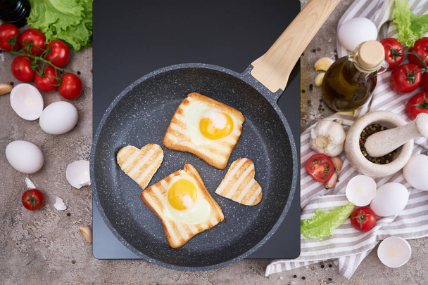 Fried egg Toasts with heart shaped holes on frying pan. - Foto, Imagem