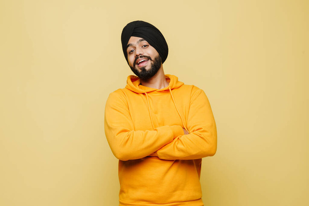 Bearded south asian man wearing turban posing with arms crossed isolated over yellow wall - Valokuva, kuva