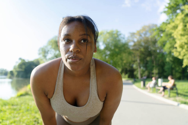 African American focused woman breathing after the running at the park   - 写真・画像
