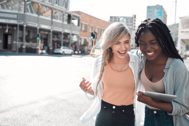 Laughing, happy and trendy students walking together in city after study class with a tablet downtown. Stylish, cool and funky women and young friends bonding, embracing and hugging on a town street. - 写真・画像
