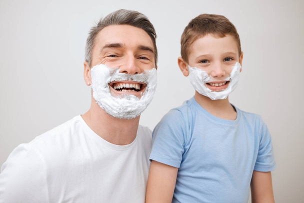 Kuin isä, kuin poika. Rajattu muotokuva komea kypsä mies opettaa nuorelle pojalleen, miten parranajo kylpyhuoneessa kotona - Valokuva, kuva