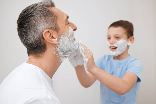 Youve gotta learn sometimes. a handsome mature man teaching his young son how to shave in the bathroom at home - Photo, Image