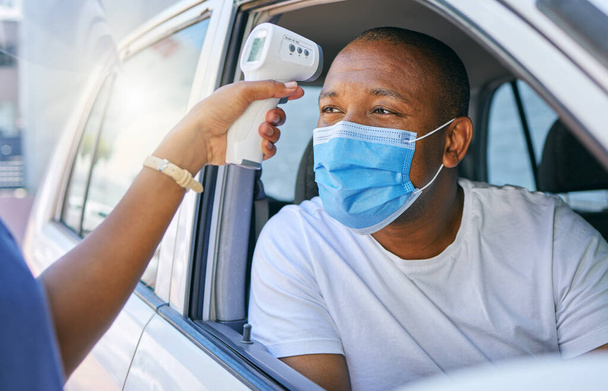 Covid, corona and infection testing site as a drive thru service station for people traveling. African man wearing a protective face mask to avoid infection and stop the spread while driving his car. - 写真・画像