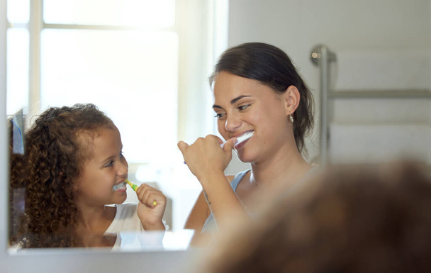 Dental care, brushing teeth and healthy routine in mother and daughter morning at home. Happy, fun and playful child and parent bonding and learning hygiene and grooming with toothpaste in a bathroom. - Photo, image