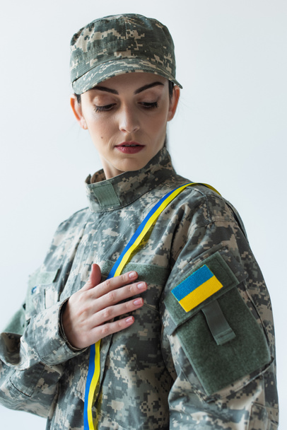 Portrait of soldier with ukrainian flag on uniform and blue and yellow ribbon isolated on grey  - Fotó, kép