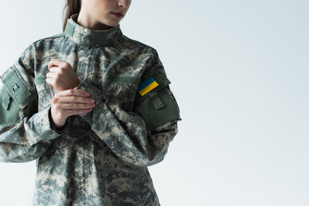 Cropped view of woman in military uniform with ukrainian flag isolated on grey  - Foto, immagini