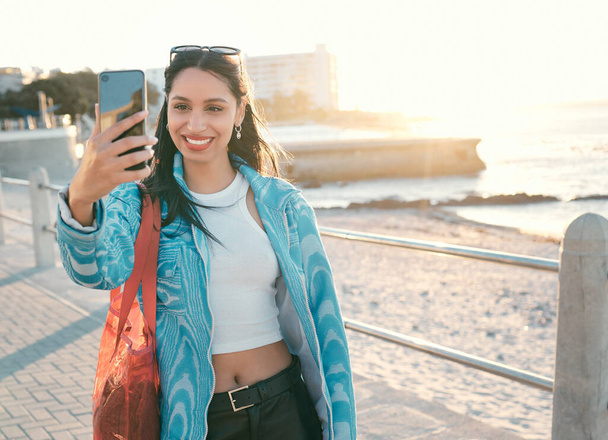 Fun, happy and trendy student taking a selfie on phone for social media while exploring, visiting and enjoying city. Beautiful, young and smiling tourist taking photos on technology on vacation. - Foto, Imagem
