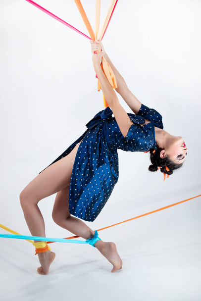 Fotografische voorstelling van een jonge vrouw verkleed als marionet gevangen door haar snaren  - Foto, afbeelding