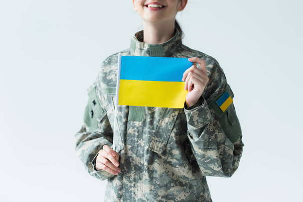 Cropped view of happy soldier holding ukrainian flag isolated on grey  - Foto, Bild