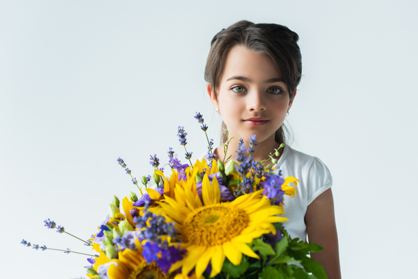 Child holding blue and yellow flowers isolated on grey  - Photo, Image
