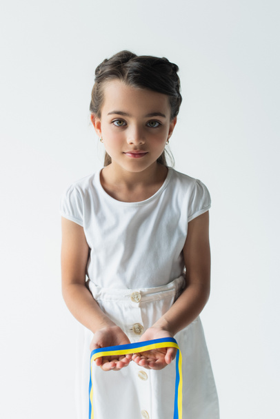 Child holding blue ad yellow ribbon and looking at camera isolated on grey  - Foto, imagen
